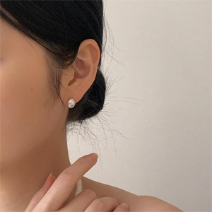 Detail of silver irregular organic stud earrings on model for a minimalist style