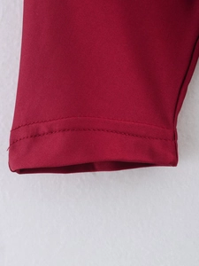 Close-up of double-needle hem stitching and plain weave texture on dark red fabric sleeve