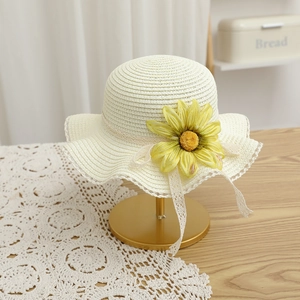 Détail d'un chapeau de paille pour enfant avec tournesol et nœud en dentelle