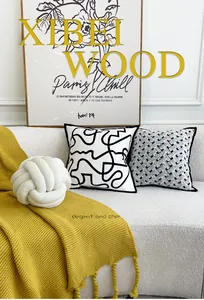 Nordic woven pillows and yellow knitted throw blanket on a minimalist white sofa