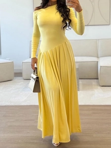 Détail d'une robe maxi jaune à manches longues avec taille asymétrique et jupe plissée