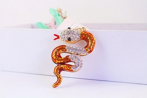 Macro detail of a golden snake pendant with white rhinestones and orange enamel scales