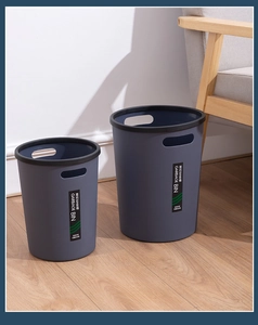 Close-up of two grey-blue trash bins with handles on wood floor in a home setting