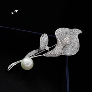 Macro shot of silver Calla Lily brooch with white crystals and a large lustrous pearl