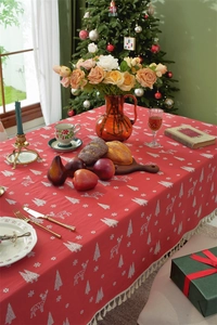 Detailed view of red Christmas tablecloth featuring white elk patterns and tassel edges