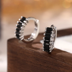 Macro detail of 925 silver hoop earrings with rectangular black cubic zirconia stones