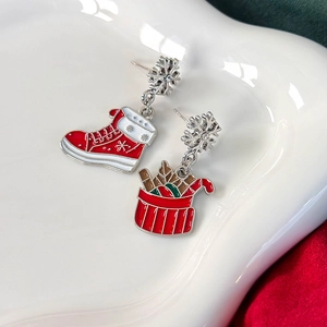Details von Weihnachts-Ohrringen mit roten Schneestiefeln und Geschenkkorb auf Keramiktablett