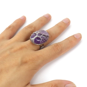 Macro detail of handmade silver wire tree of life wrapping on purple oval crystal ring