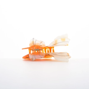 Detail view showing the spring mechanism of an orange fish-shaped acrylic hair claw clip