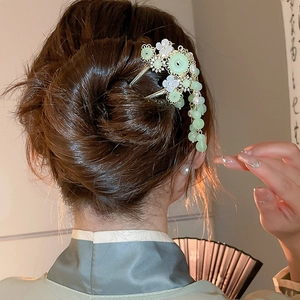 Details einer chinesischen Haarnadel mit grünen Perlen und Blumenquasten an einem Dutt