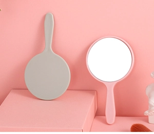 Detail of pink and grey handheld mini makeup mirrors with ergonomic plastic handles