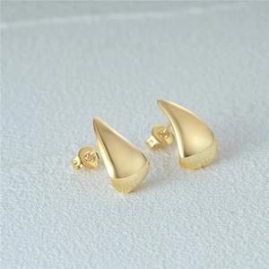 Macro shot of minimalist gold teardrop stud earrings with smooth metallic finish