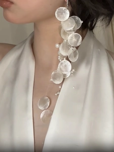 Detailed view of long shell tassel earrings with white pearls on a model