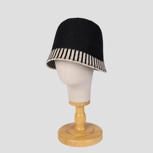 Women's black knit bucket hat with beige striped brim on a mannequin head display