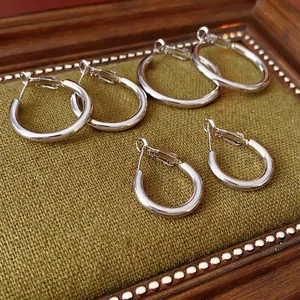 Three pairs of silver hoop earrings in small, medium and large sizes on green fabric