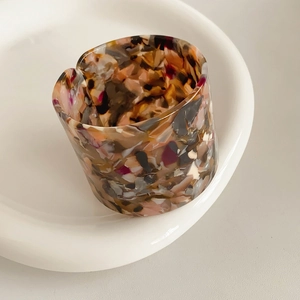 Detailed macro view of retro acetate ring with brown marble texture on ceramic plate