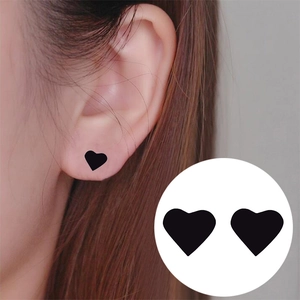 Minimalist matte black heart stud earrings in stainless steel shown worn on ear