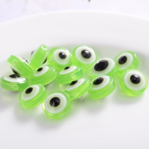 Close-up of green resin evil eye beads with concentric circles on a white plate