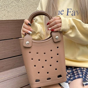Close-up of khaki waterproof EVA tote bag with hole design held by a model on a bench