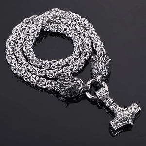 Macro detail of Nordic Viking Thor's Hammer necklace with twin wolf heads in silver finish