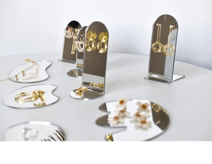 Macro view of minimalist acrylic mirror jewelry display trays with golden earrings