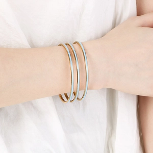 Close-up of three slim 3mm gold and light blue enamel stackable stainless steel bangles