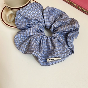 Detail of blue and white plaid scrunchie with cotton fabric texture and cloth brand label