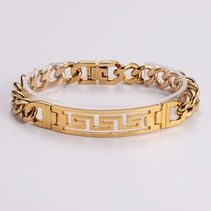 Macro detail of gold stainless steel Cuban link bracelet with Greek key cutout plaque