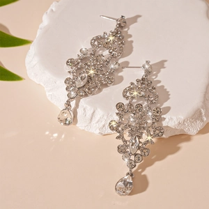 Detailed close-up of sparkling silver drop earrings with rhinestones on stone pedestal