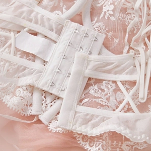 Detailed macro view of white floral lace lingerie featuring triple row hook-and-eye closure