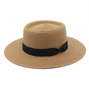 Detail of tight weave texture and black grosgrain ribbon on khaki boater straw hat
