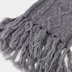 Detailed macro shot of dark grey cable knit scarf with thick tassels and texture