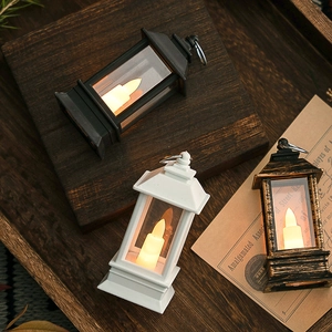 Faroles LED vintage en negro, blanco y bronce sobre una bandeja madera