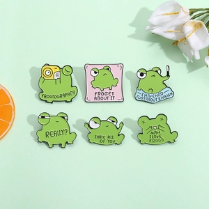 Set of six cute cartoon green frog enamel pins with humorous quotes on a pale green background