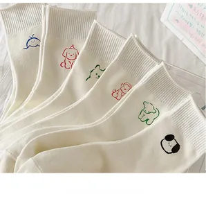 Detail of six pairs of cream white cotton socks with colorful cartoon animal embroidery
