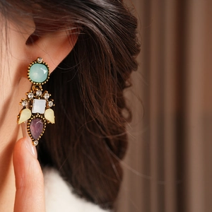 Close-up of vintage flower earrings with colorful gems and antique gold finish on model