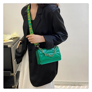 Detail of green quilted crossbody bag with a branded yellow jacquard wide strap