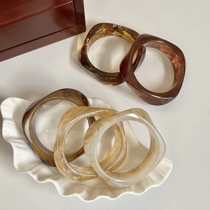 Detailed set of five marbled resin bangles in coffee tones on a ceramic dish