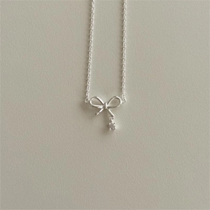 Minimalist S925 sterling silver bow necklace with sparkling zircon on cream background