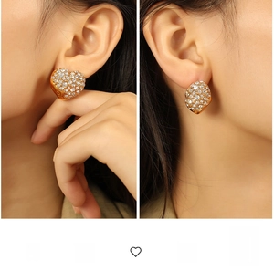 Close-up of sparkling heart-shaped gold stud earrings with pavé set crystals on a model