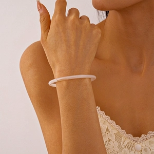 Gros plan d'un bracelet fin en résine acrylique rose laiteux porté par une femme