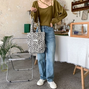 Leopard print canvas tote bag styled with green knitwear in a vintage cafe setting