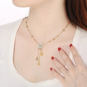 Detail of a gold butterfly necklace featuring enamel accents and dangling charms on a model