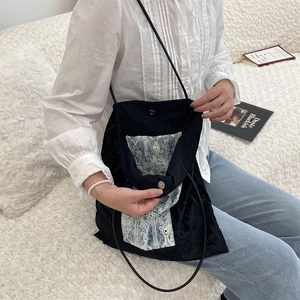 Detail of the black canvas tote bag showing magnetic closure and lace lining design
