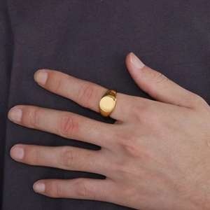 Polished 18K gold plated stainless steel signet ring on finger against grey fabric