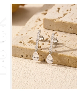 Macro shot of silver S925 earrings with pear-cut crystals on a textured stone base