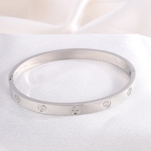 Detailed close-up of a silver stainless steel bangle with engraved radial sunburst patterns