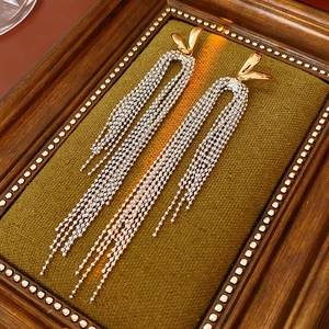 Detail of 18k gold plated long tassel earrings on a vintage dark green velvet pad
