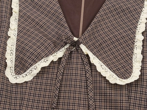 Detail of V-neckline with cream lace collar and plaid bow on checkered dress