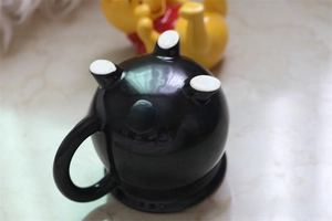 Close-up of black ceramic cauldron mug showing the unique four-legged base design